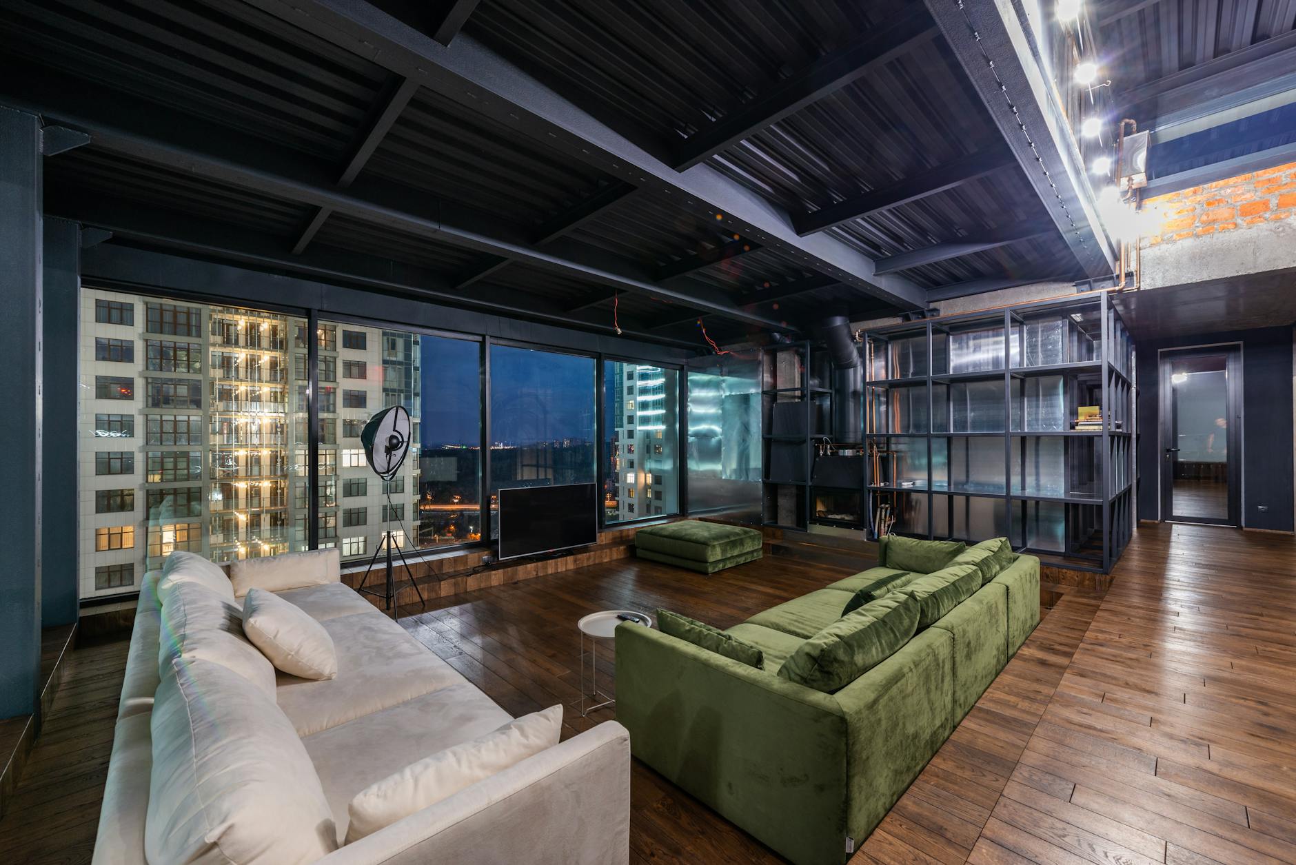 Nowoczesny przestronny salon w lofcie z dużymi oknami i widokiem na miasto